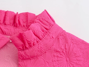 Detail of rose pink mini dress featuring textured jacquard fabric and ruffled collar neckline