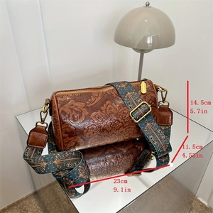 Vintage brown embossed leather cylinder bag with colorful jacquard strap on mirror surface