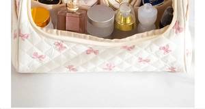 Interior view of large quilted cosmetic bag with pink bows and organized skincare items