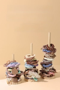 Three-tier wooden hair tie stand showcasing various scrunchies and bracelets