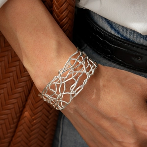 Close-up of a silver-toned wide lattice cuff bracelet worn on a model's wrist