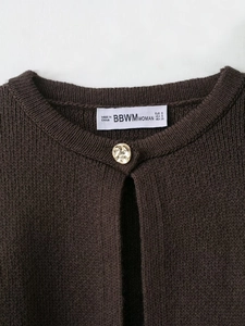 Vue détaillée du cardigan en maille marron foncé avec bouton doré gravé et étiquette de marque