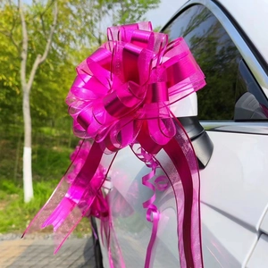 Macro shot of large magenta car mirror bow made of satin and plastic ribbon on a white car