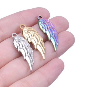 Macro shot of three wing charms in gold, silver and rainbow colors on a palm
