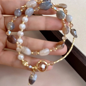Detail view of pearl and crystal beaded bracelets with gold spacer beads on hand
