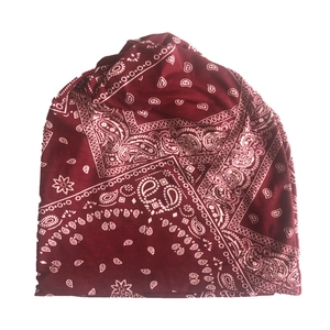 Close-up detail of red paisley pattern on knitted slouchy beanie with white floral motifs