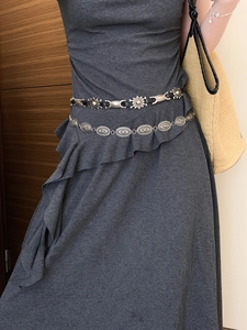 Detail of vintage silver oval metal chain and black sun pattern belt on a female model