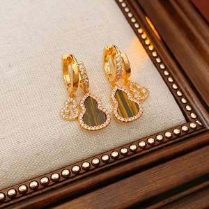 Detail of gold gourd earrings with tiger eye stone and zircon on wooden display