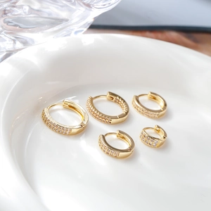 Detailed view of five sizes of gold plated hoop earrings with zircon pavé on a ceramic tray
