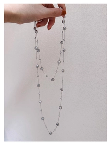 Detailed view of silver metallic beads and long thin chain necklace with sleek finish