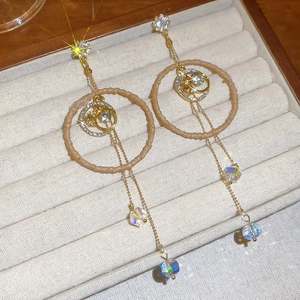Detail of bohemian drop earrings with woven rings and faceted crystal tassels on velvet
