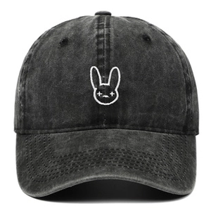 Detail of white Bad Bunny logo embroidery on washed black denim baseball cap fabric