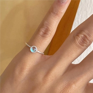 Detail of a 925 silver ring with a blue gemstone and beaded bezel setting on a finger