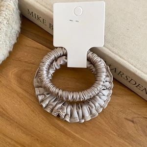 Détail de chouchous en satin plissé champagne sur table en bois avec livre de style vintage
