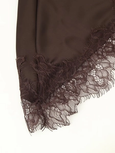 Detailed macro view of dark brown satin fabric with delicate lace trim on a dress