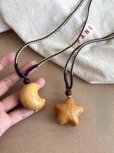 Macro view of hand-carved wooden star and moon pendants with rustic braided rope cords