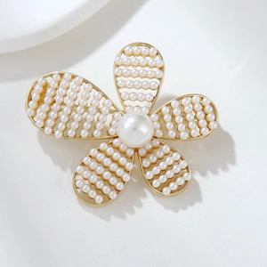 Detailed macro view of camellia brooch with gold mesh petals and white pearls inlay