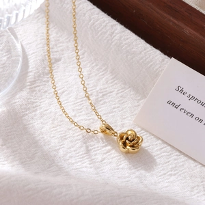 Elegant gold rose pendant necklace for women on a textured white fabric background