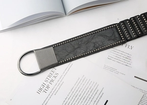 Macro detail of black punk waist belt featuring silver metal studs and D-ring buckle