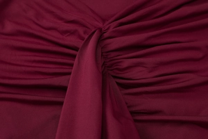 Detailed view of dark red waist twist knot design and smooth fabric texture on dress