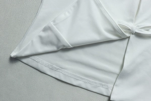 Détail de l'ensemble jupe blanche montrant les ourlets et le laçage décoratif latéral