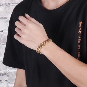 Close-up of a bold gold-finished stainless steel Cuban link bracelet on a male wrist