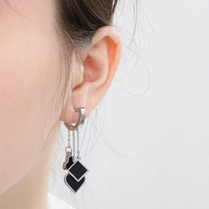 Macro shot of silver tassel earrings featuring black clover, heart and spade charms