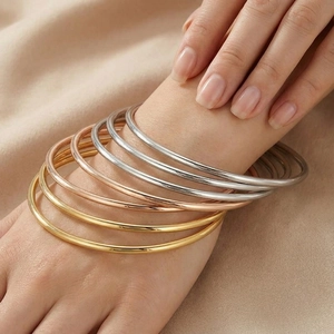 Close-up of stacked 3mm stainless steel bangles in gold, rose gold and silver finishes