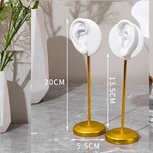Detailed view of white resin ear model jewelry stands with golden metal rods and bases