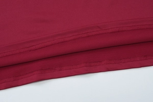Makroaufnahme der Doppelnadelnaht am burgunderroten Strickkleid-Saum und Ärmel