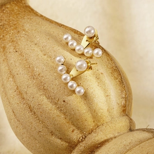 Boucles d'oreilles élégantes en perles plaqué or 18K sur un socle de colonne en pierre