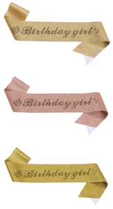 Detail of three glitter Birthday Girl sashes in gold, rose gold and light gold colors