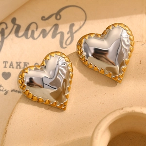Detailed close-up of two-tone heart stud earrings with silver mirror and gold trim