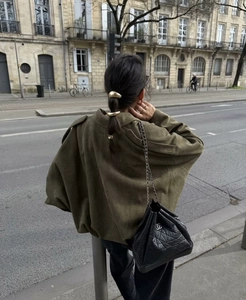 Dettaglio della giacca bomber in camoscio verde con accessori in metallo dorato