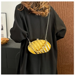 Detailed view of golden seashell clutch with wavy textures and elegant beaded metal chain