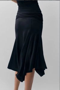 Détail de la jupe longue noire en maille avec fronces latérales et coupe asymétrique
