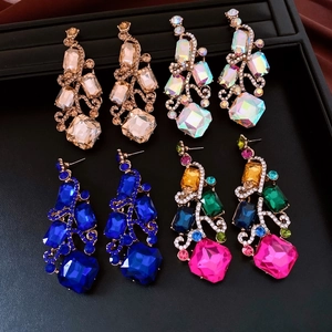 Detailed close-up of four geometric rhinestone pendant earrings on a black display stand