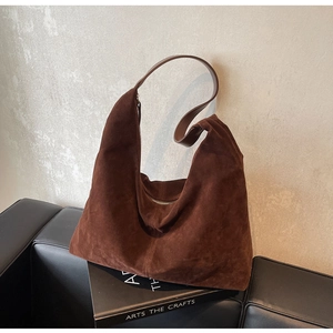 Detailed texture of brown suede hobo bag placed on a black art book with soft lighting