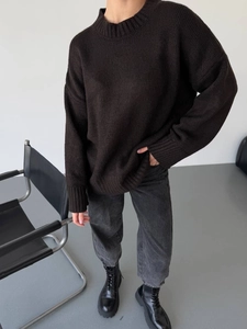Full body view of relaxed oversize dark knit sweater paired with grey jeans and boots