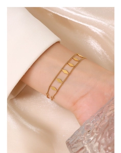 Close-up of double-layer gold geometric rhombus bracelet on a white blazer sleeve