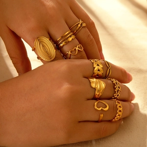 Macro shot of 18K gold plated heart and textured rings layered on a linen background