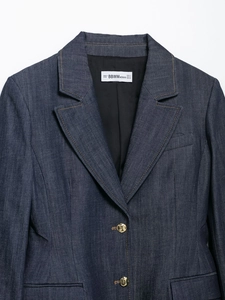 Dettaglio del colletto del blazer in denim con bottoni dorati ed etichetta BBWMwoman
