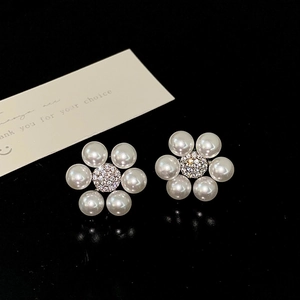 Macro detail of elegant pearl flower earrings with a shimmering rhinestone center