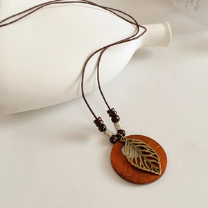 Détail du pendentif feuille évidée sur perle en bois avec finition bronze antique