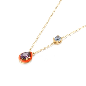 Detailed macro view of gold plated necklace with purple water drop gem and orange enamel