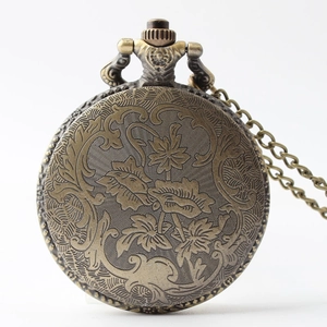 Detailed close-up of retro bronze pocket watch with floral relief carvings and metal chain