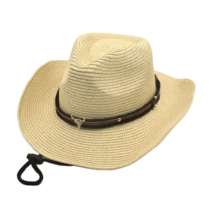 Detail view of woven straw cowboy hat featuring a golden bull head badge and leather band