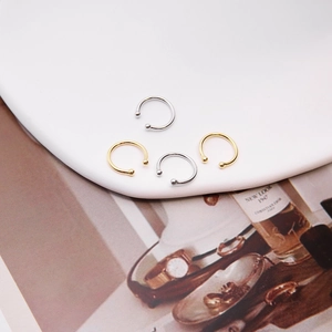 Detailed view of silver and gold C-shaped ear cuffs on a minimalist white display tray