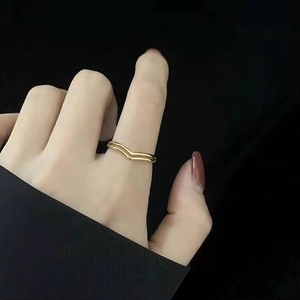 Detailed close-up of double-layer V-shaped 18K gold ring on finger with black background
