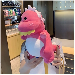 Detailed view of plush pink dinosaur crossbody bag with white belly and yellow strap
